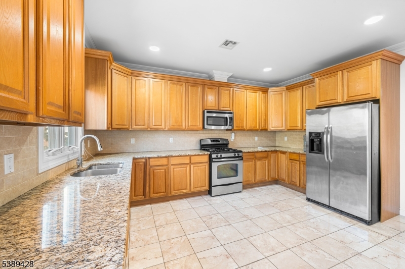 233 5th Street, Unit B Fairview, NJ 07022 - Photo 11 of 31 a kitchen with stainless steel appliances granite countertop a refrigerator sink and stove
