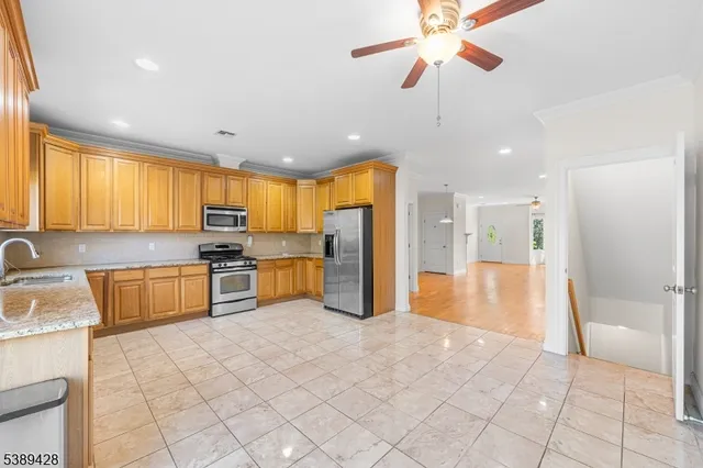 a large kitchen with stainless steel appliances kitchen island granite countertop a refrigerator oven a sink a dining table and chairs with wooden floor