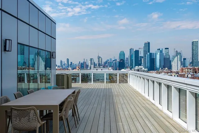 a view of a roof deck with table and chairs a barbeque with wooden floor and fence