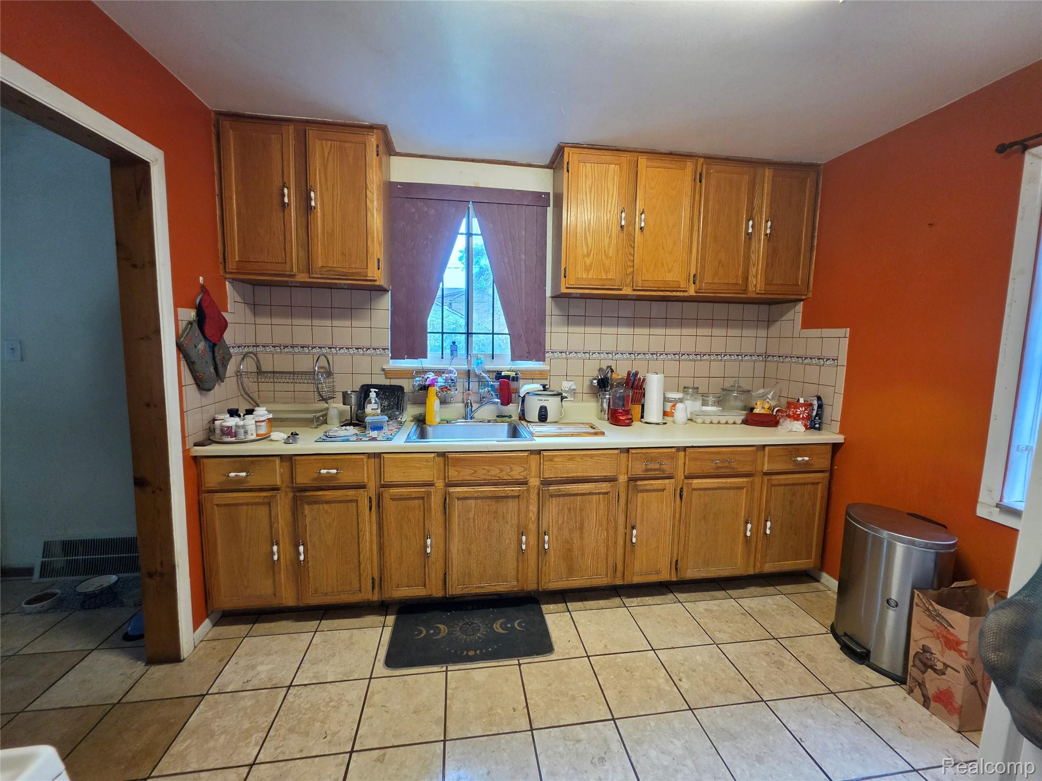 15832 Griggs Street Detroit, MI 48238 - Photo 11 of 24 Kitchen featuring wood cabinetry, a window with a valance, and a tiled backsplash