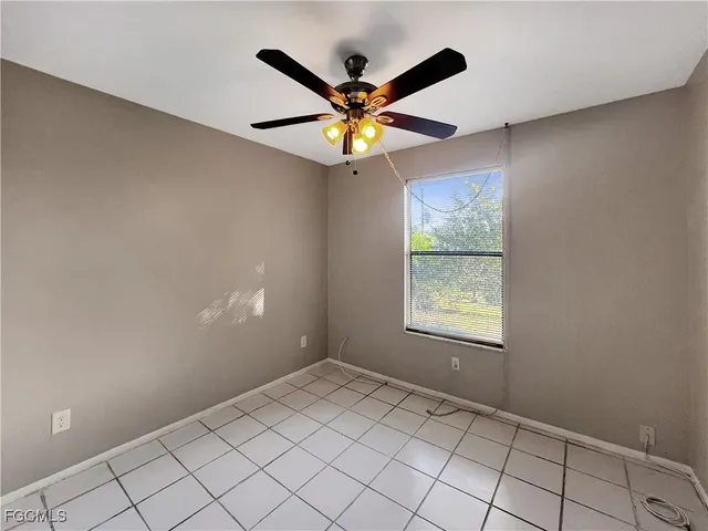 a view of an empty room and window with a ceiling fan