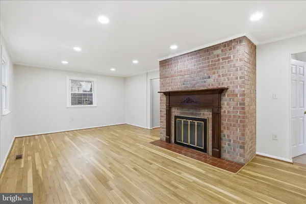 a view of an empty room with wooden floor and a fireplace