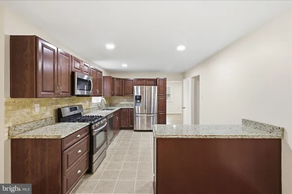 a kitchen with stainless steel appliances granite countertop a stove a sink dishwasher a refrigerator and a microwave