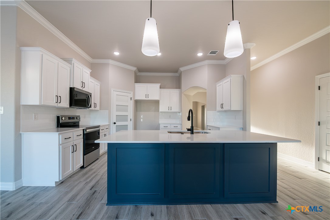 1404 Red Rock Road Hewitt, TX 76643 - Photo 12 of 30 a kitchen with stainless steel appliances a sink a stove a microwave a center island and cabinets