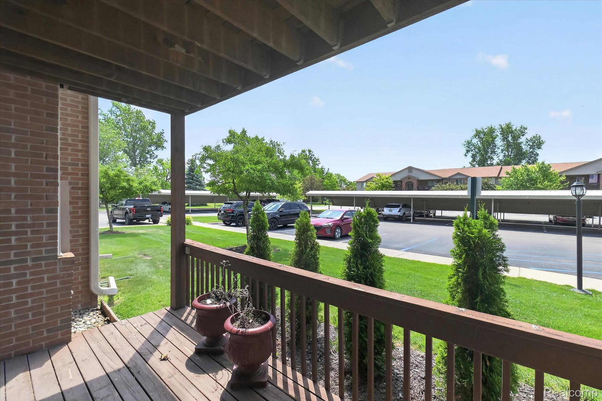 45720 Prairiegrass Court Belleville, MI 48111 - Photo 29 of 31 Ground-level patio with wood deck flooring, wood railing, brick exterior, and landscaped greenery