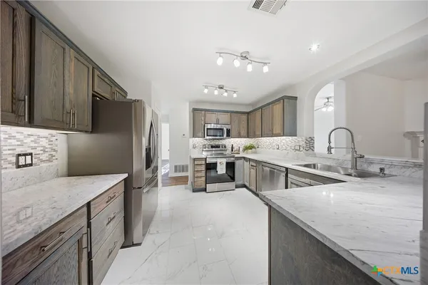 a kitchen with stainless steel appliances granite countertop a sink stove and refrigerator