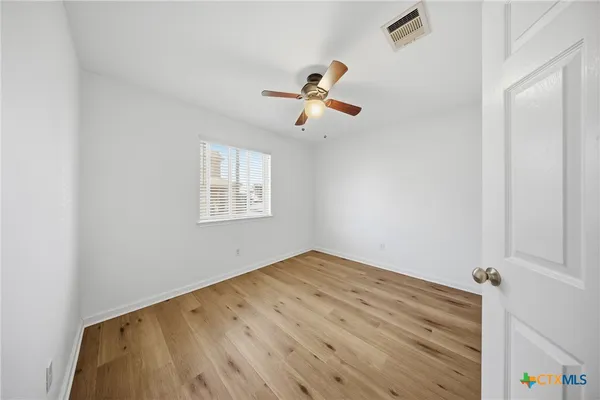an empty room with a window and ceiling fan