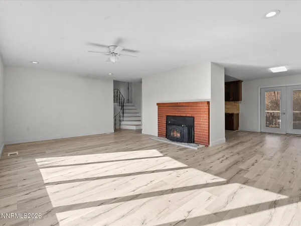 a view of an empty room with wooden floor fireplace and a window