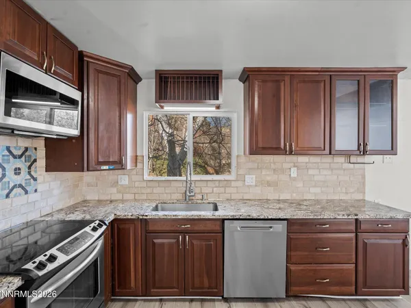 a kitchen with granite countertop stainless steel appliances a sink stove and cabinets