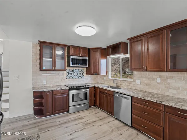 a kitchen with stainless steel appliances granite countertop wooden cabinets and a sink