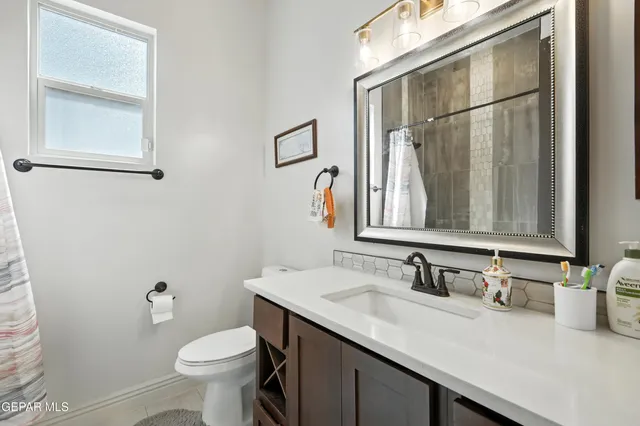 a bathroom with a granite countertop sink toilet and mirror