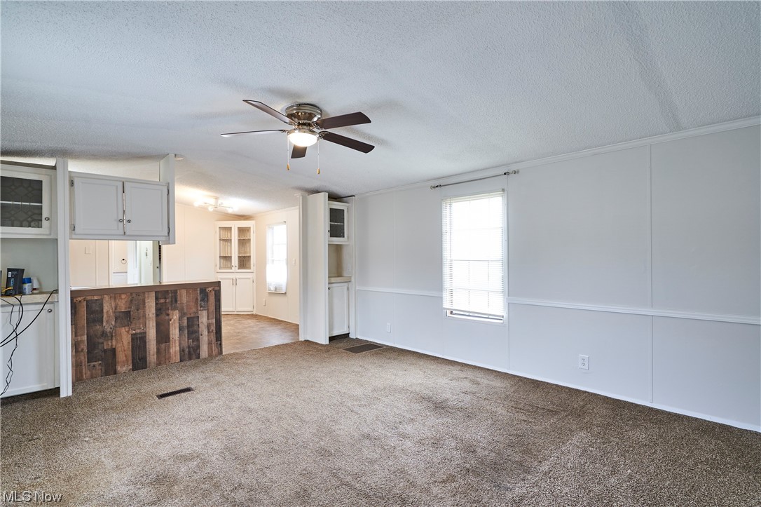 45 Eddie Road Madison, OH 44057 - Photo 6 of 26 Unfurnished living room with dark colored carpet, ceiling fan, a textured ceiling, and vaulted ceiling