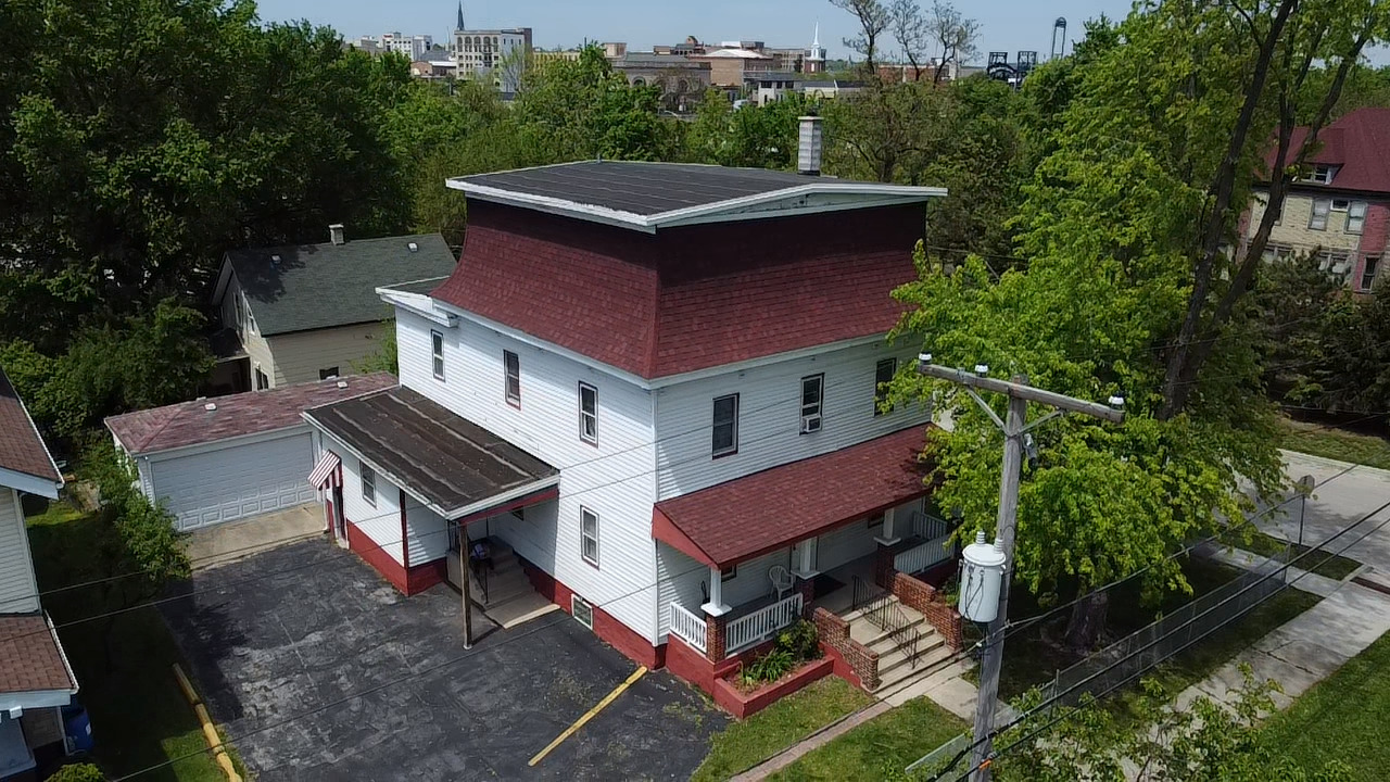 a red brick house with a clock tower in middle of garden