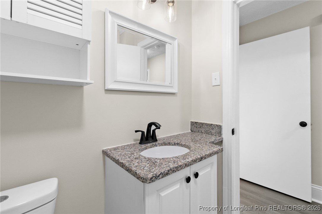 2712 Morganton Road Fayetteville, NC 28303 - Photo 26 of 39 a bathroom with a granite countertop sink and a toilet
