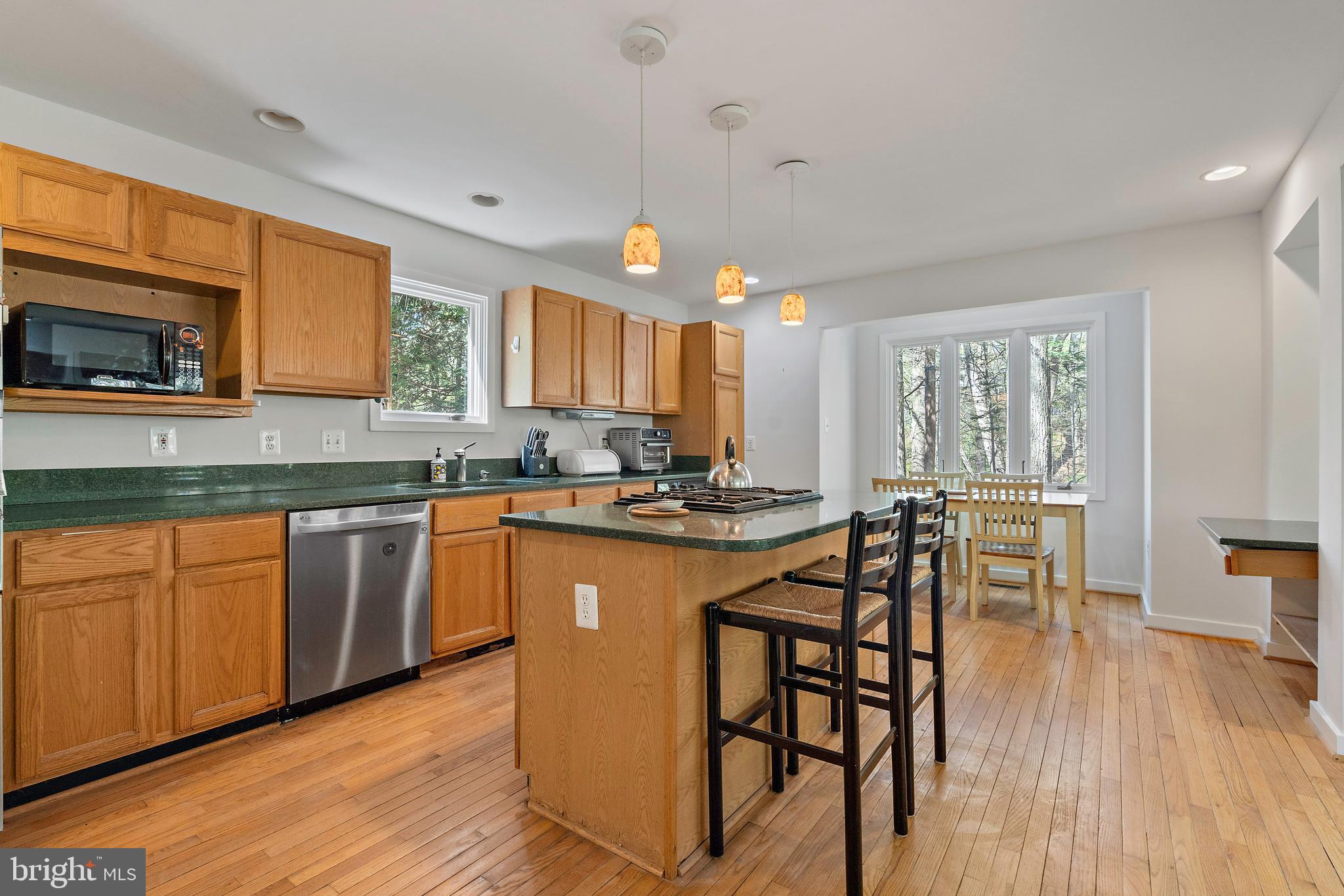 132 Hilltop Road Silver Spring, MD 20910 - Photo 6 of 50 a kitchen with stainless steel appliances granite countertop wooden floor a stove a sink dishwasher a microwave oven and a dining table with wooden floor