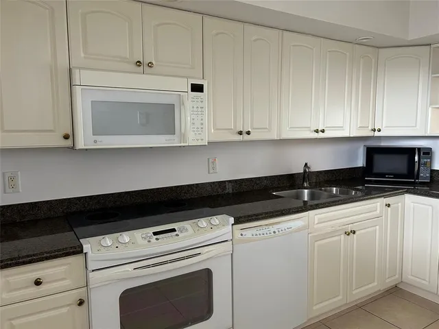 a kitchen with white cabinets and sink