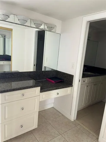 a kitchen with white cabinets and sink