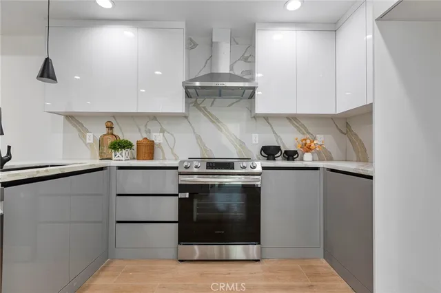 a kitchen with stainless steel appliances granite countertop a stove a refrigerator and a sink with wooden floor