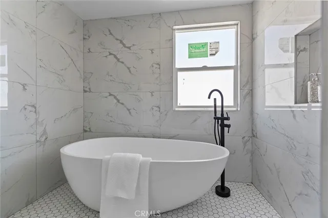 a white bath tub sitting in a bathroom next to a window