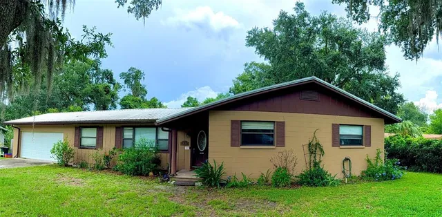 a view of a yard in front of a house with plants and large tree