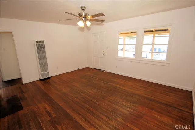 an empty room with wooden floor and window