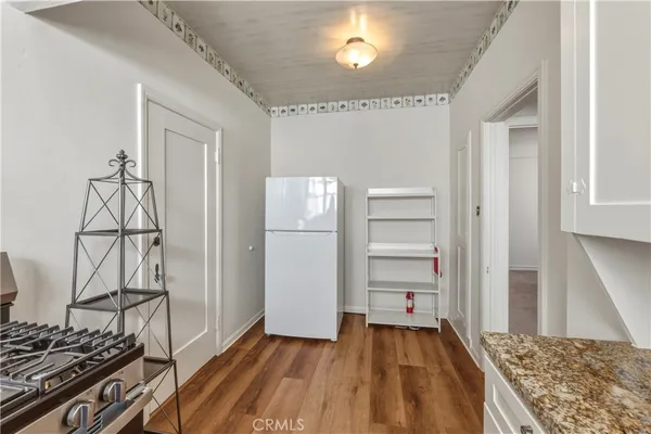a view of a livingroom with wooden floor and kitchen space