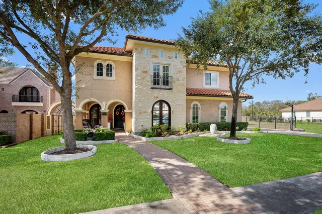 a front view of a house with garden and trees