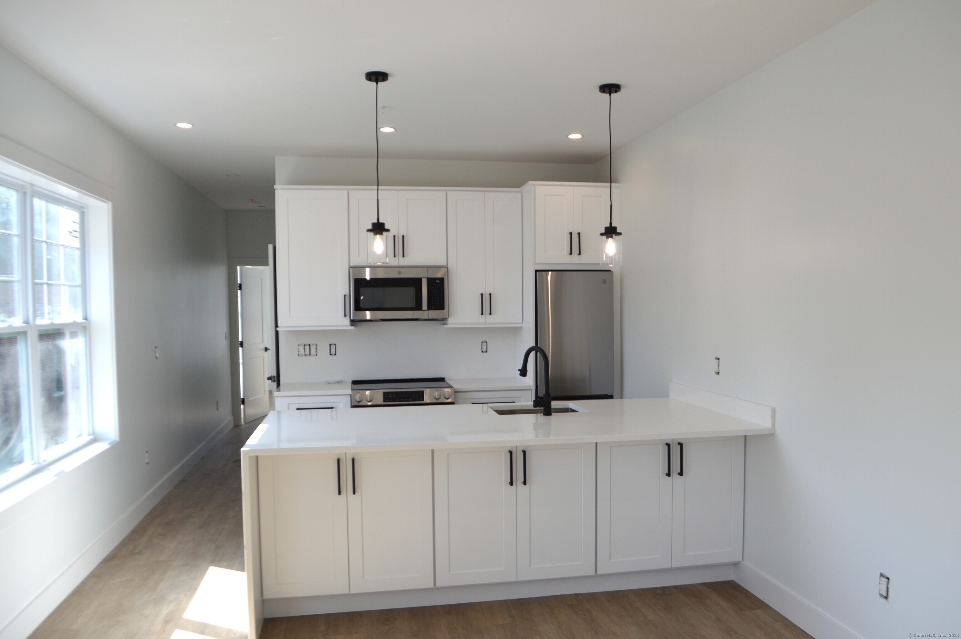 25 Church Street, Unit 106 New Milford, CT 06776 - Photo 2 of 11 a kitchen with white cabinets and refrigerator
