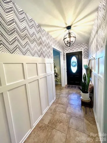 a view of a hallway with wooden floor and a chandelier