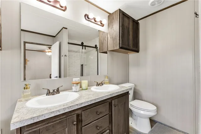 a bathroom with a granite countertop sink a toilet and mirror