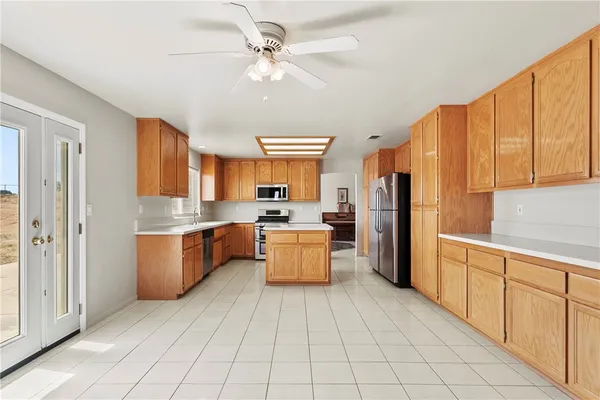 a large kitchen with a large counter top space a sink stainless steel appliances and cabinets