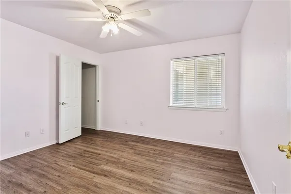 an empty room with wooden floor chandelier fan and windows