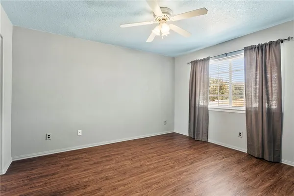 an empty room with wooden floor fan and windows