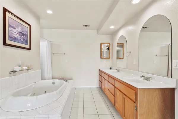 a spacious bathroom with a tub sink and mirror