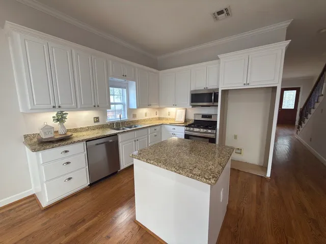 a kitchen with granite countertop a refrigerator stove top oven and sink