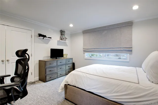 a bedroom with a bed and a flat tv screen on the dresser