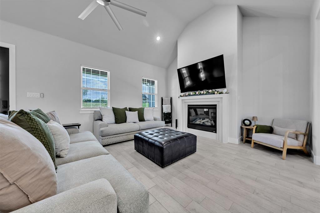 2004 Willy Dilly Road Springtown, TX 76082 - Photo 10 of 40 Vaulted ceiling living area featuring a built-in fireplace with white mantel, light wood-finish flooring, and multiple windows