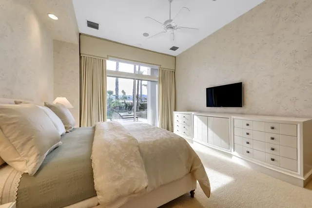 a bedroom with a large bed and a flat tv screen on dresser