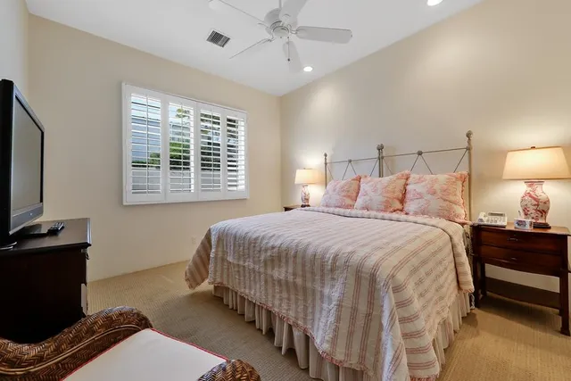a bedroom with a bed and a flat tv screen on dresser
