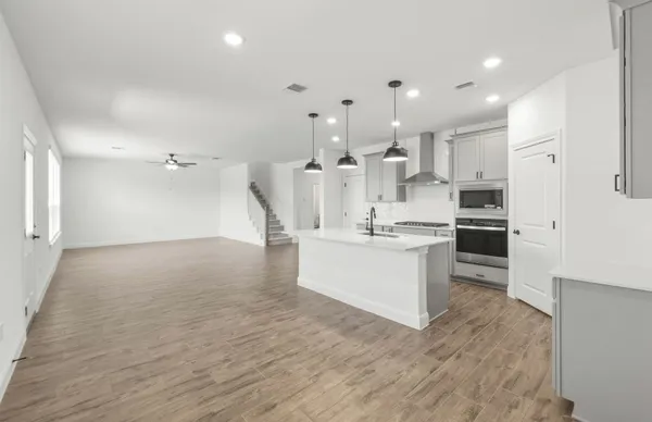 a kitchen that has a sink a microwave oven a stove and white cabinets with wooden floor