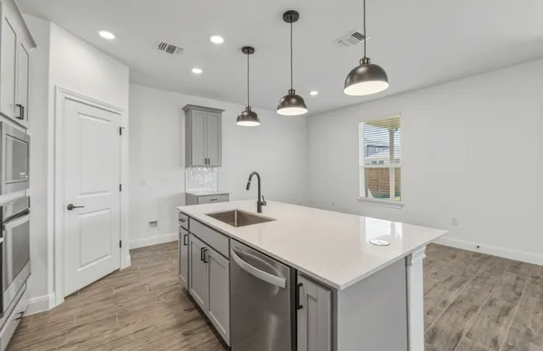 a kitchen with stainless steel appliances granite countertop a sink a oven and a chandelier