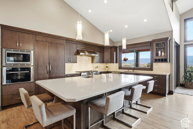 1130 Pace Road Park City, UT 84098 - Photo 19 of 73 Vaulted ceiling with recessed lighting, large central island with light-toned countertop, wood-finish flooring, built-in double oven, and integrated cabinetry