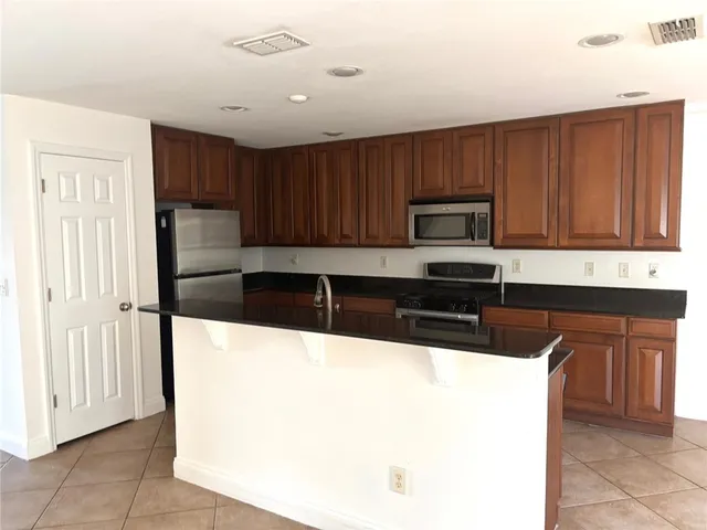 a kitchen with granite countertop wooden cabinets a refrigerator and a stove