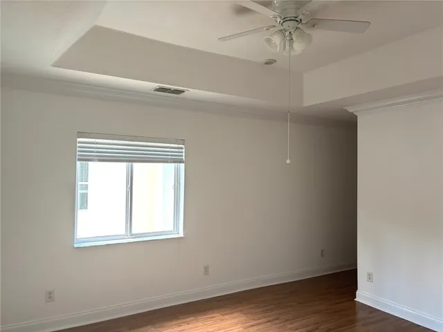 an empty room with wooden floor closet and windows