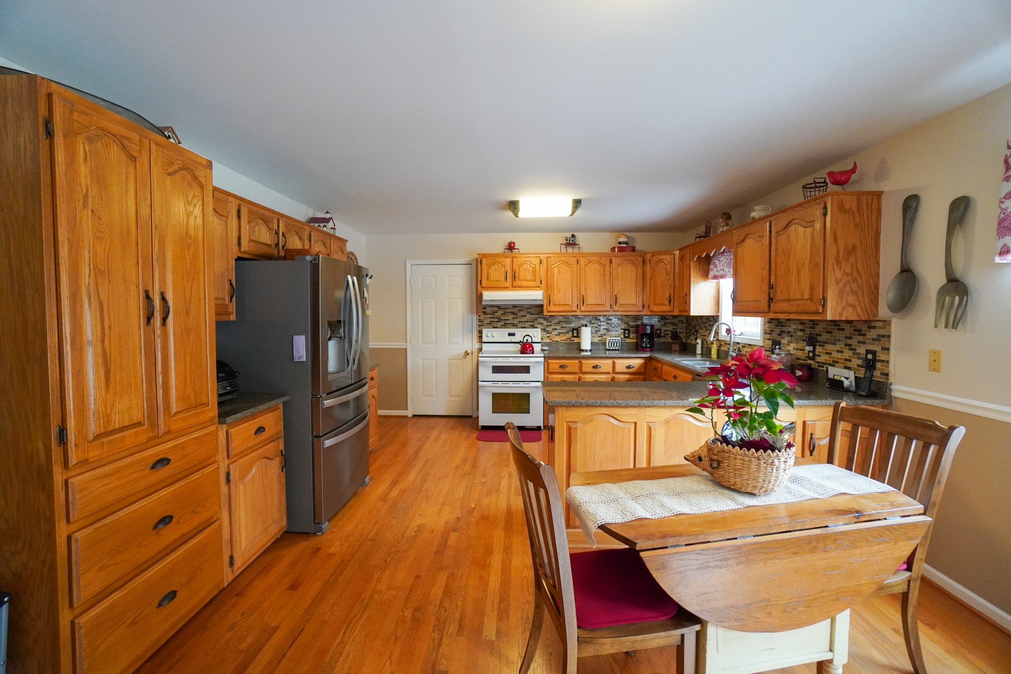 1890 Clara Mathis Road Spring Hill, TN 37174 - Photo 21 of 45 a kitchen with stainless steel appliances kitchen island granite countertop a refrigerator a stove top oven and a dining table with wooden floor
