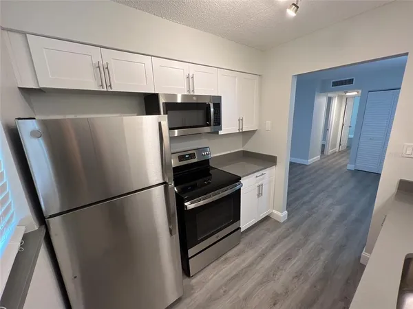 a kitchen with stainless steel appliances a refrigerator a sink and white cabinets