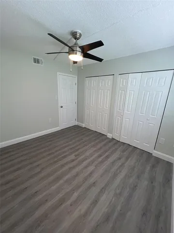 an empty room with wooden floor fan and windows