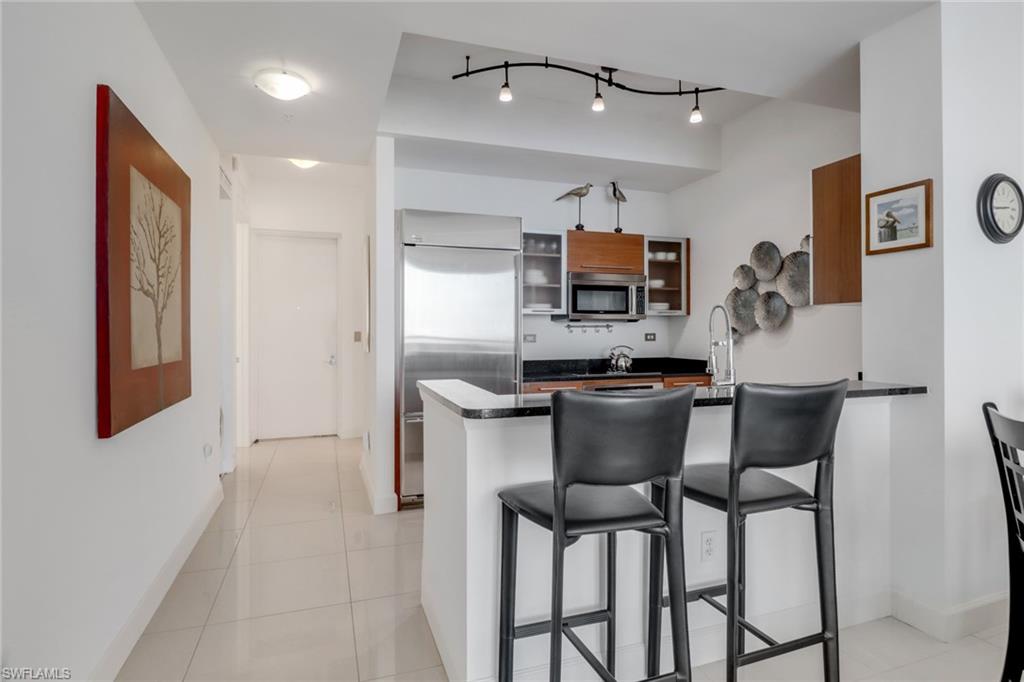 3000 Oasis Grand Boulevard, Unit MPH6 Fort Myers, FL 33916 - Photo 9 of 44 Kitchen with appliances with stainless steel finishes, dark countertops, a peninsula, a breakfast bar, and baseboards