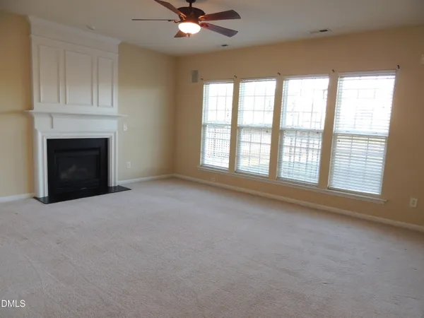 a view of an empty room with a window and fireplace