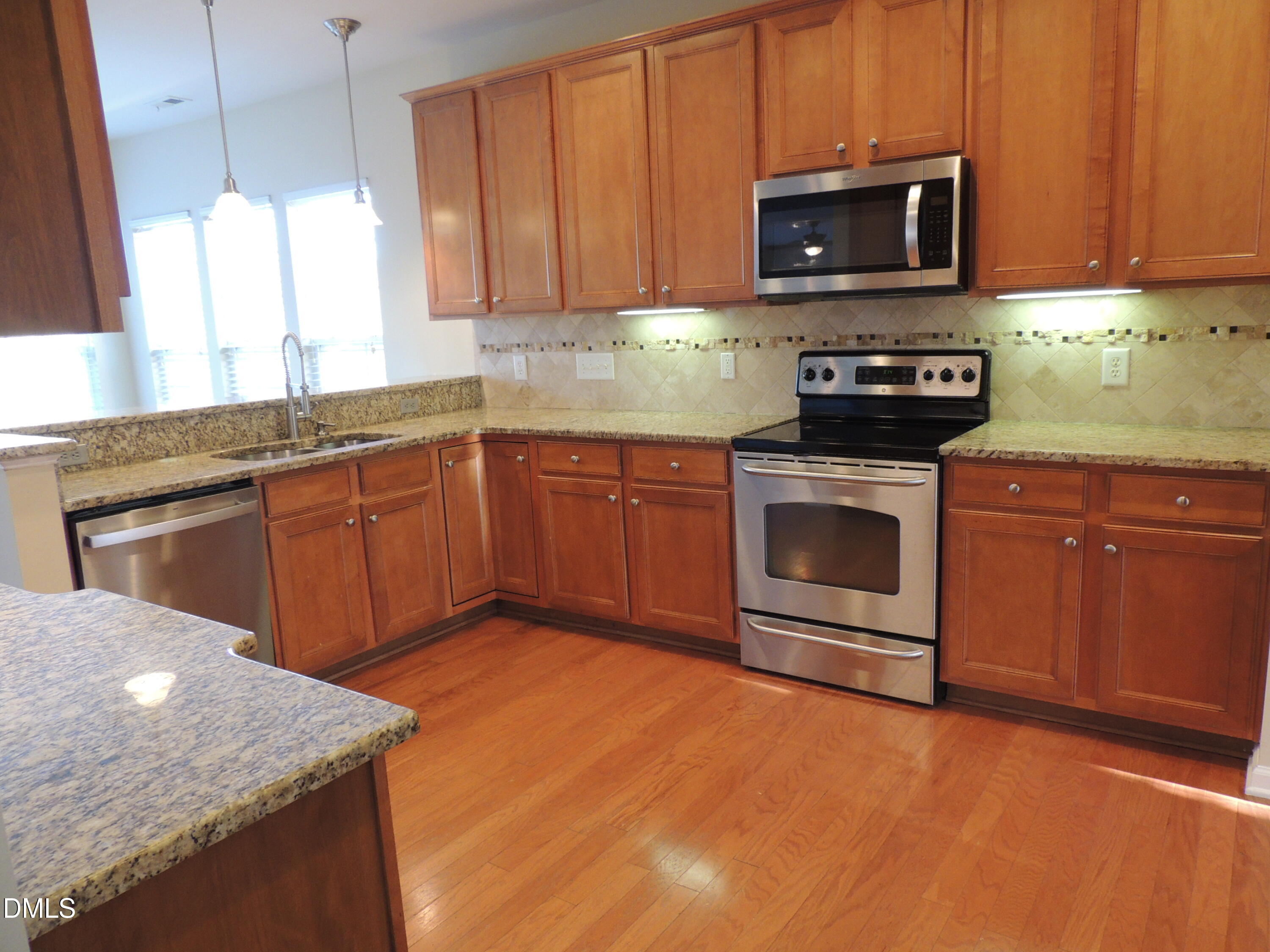 12544 Honeychurch Street Raleigh, NC 27614 - Photo 4 of 24 a kitchen with stainless steel appliances granite countertop a sink a stove a microwave and wooden cabinets